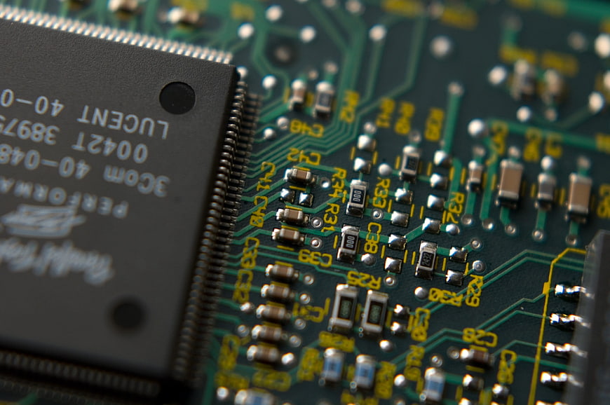 Close-up of green circuit board with microchip and electronic components
