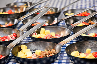 Rows of frying pans with breakfast ingredients on checkered tablecloth