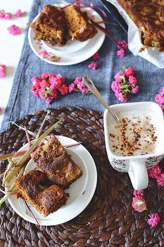 Homemade rhubarb cake slices with frothy coffee and pink flowers