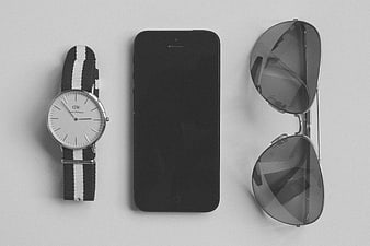 Minimalist flat lay of watch, smartphone, and sunglasses