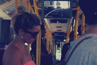 Woman with Sunglasses and Earbuds on Public Bus