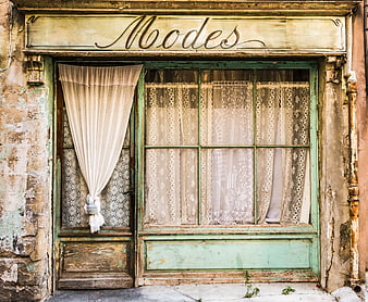 Vintage Fashion Storefront with Peeling Paint and Lace Curtains