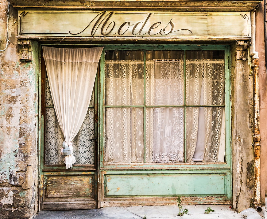Vintage Fashion Storefront with Peeling Paint and Lace Curtains