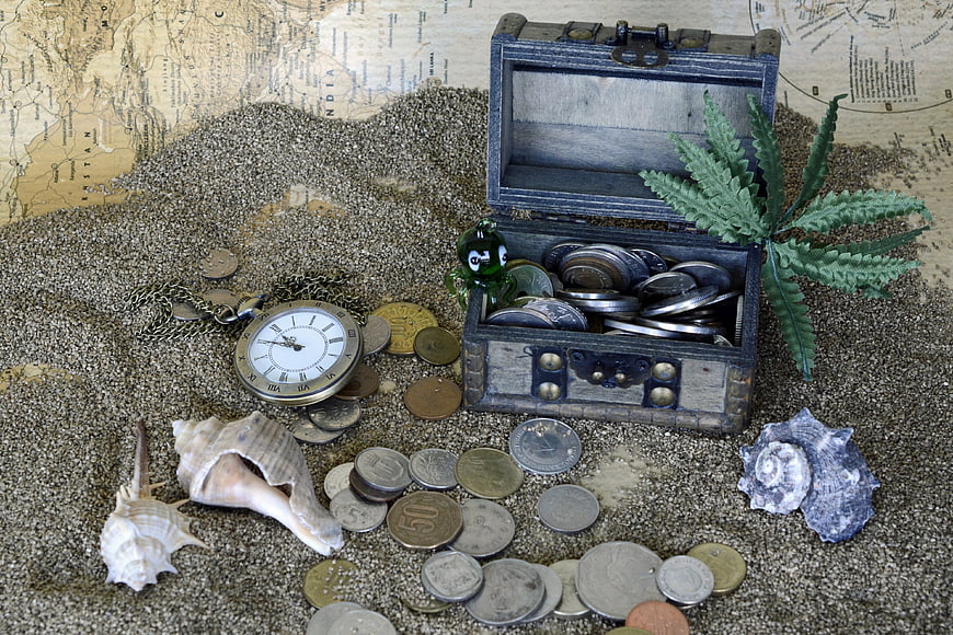 Vintage Treasure Chest With Coins, Pocket Watch, Shells, And Sand On Old Map