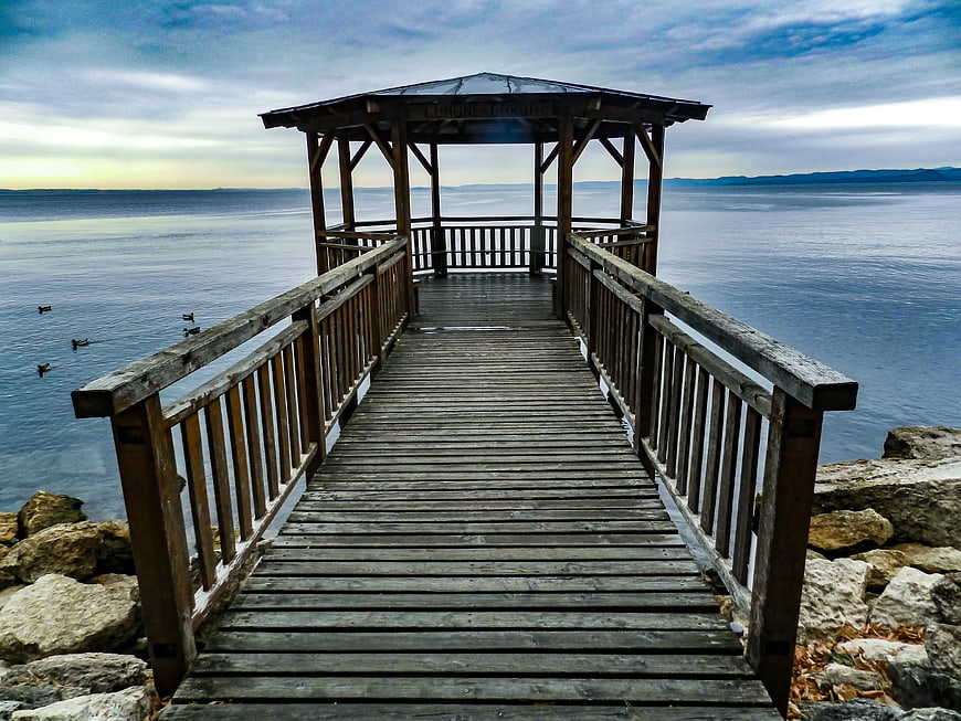 Wooden Pier with Gazebo Extending Over Calm Blue Water