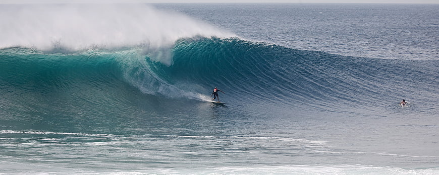 Surfer riding massive turquoise wave at Tuju Coast, West Java
