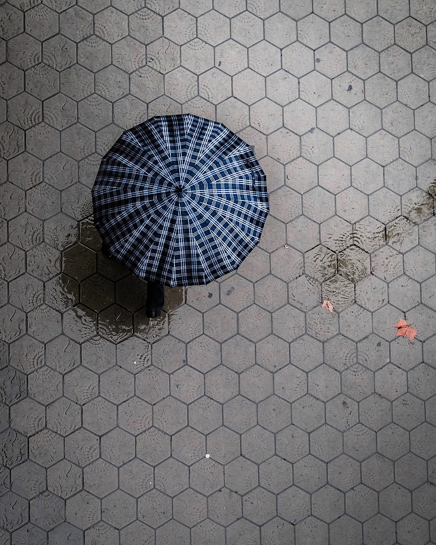 Top View of Plaid Umbrella on Wet Hexagonal Pavement