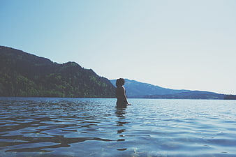Woman Standing in Lake Water with Mountain Landscape Background
