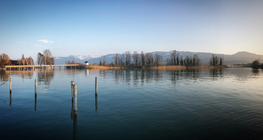 Serene Lake Landscape with Wooden Pier and Mountain Reflections