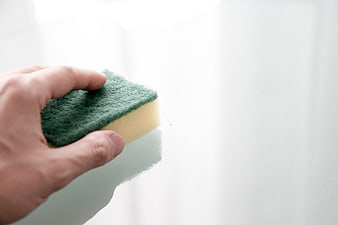 Hand Cleaning Glass with Green Sponge