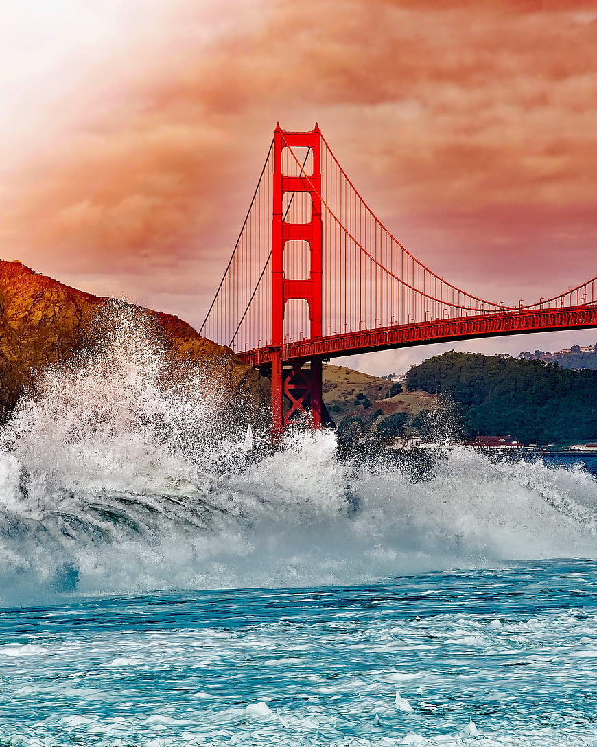 Golden Gate Bridge with dramatic crashing waves and sunset sky