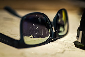Close-up of sunglasses reflecting a camera lens