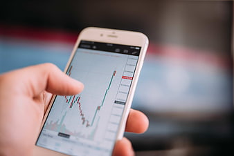 Hand holding smartphone with cryptocurrency trading chart