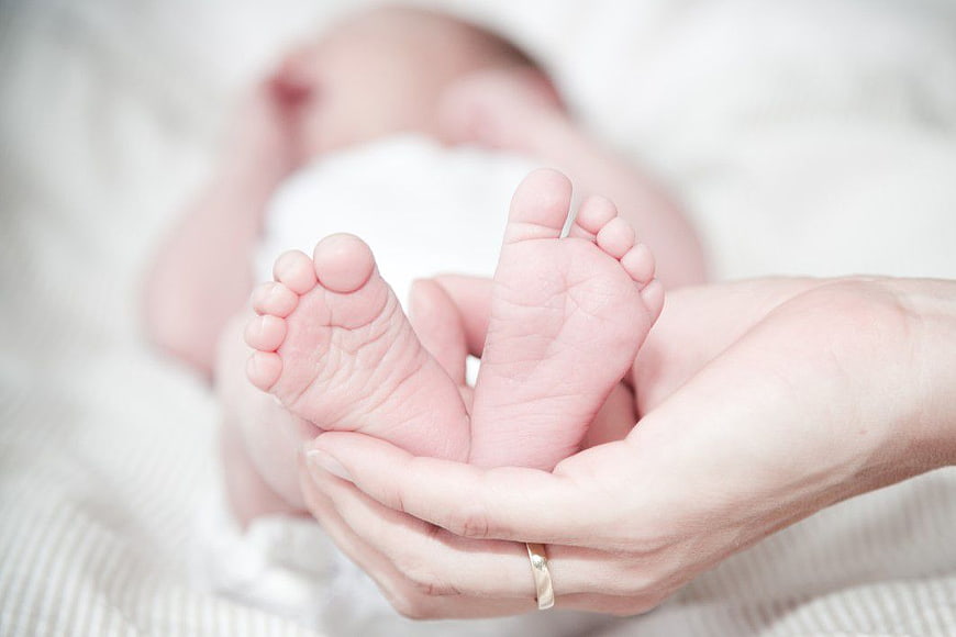 Mother's Hands Holding Tiny Newborn Baby Feet
