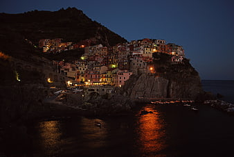 Colorful coastal village on cliffs at night with sea reflections