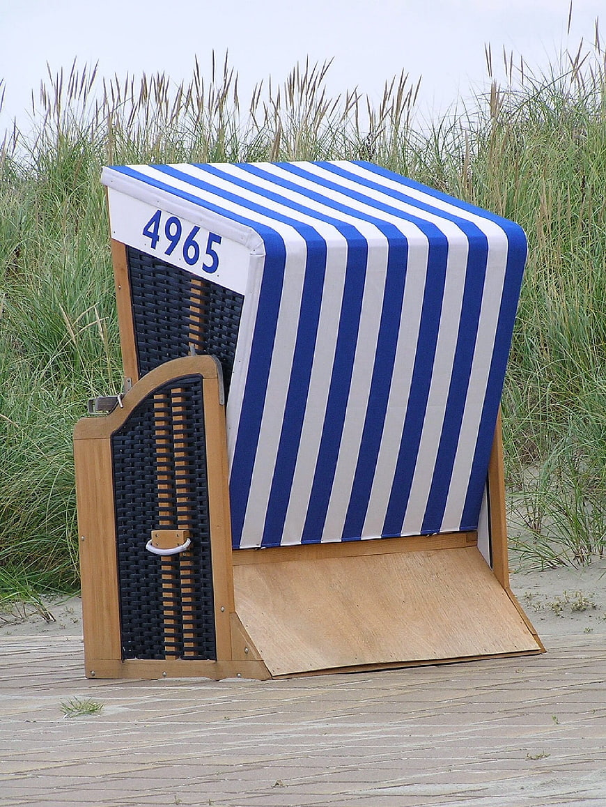 Blue and white striped German beach chair on wooden boardwalk