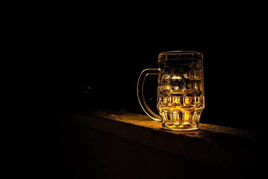 Illuminated Glass Beer Mug on Wooden Surface at Night
