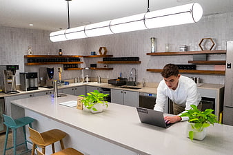 Young man working on laptop in modern office kitchen