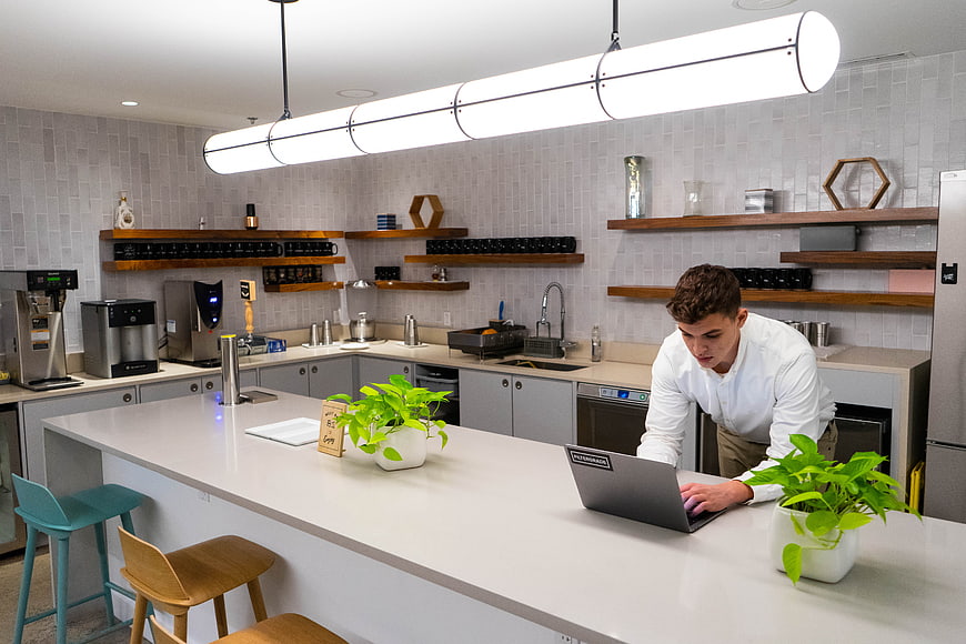Young man working on laptop in modern office kitchen