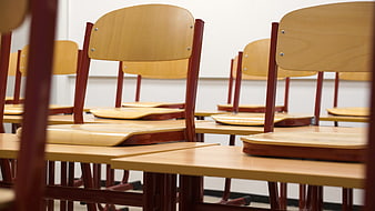 Empty wooden chairs and desks in a classroom