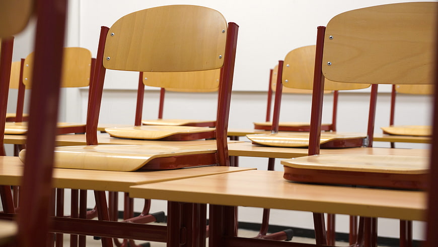 Empty wooden chairs and desks in a classroom