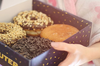 Hand holding box of assorted gourmet donuts