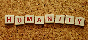 Humanity spelled with wooden letter tiles on cork board