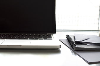 Minimalist workspace with laptop and notebook on white desk