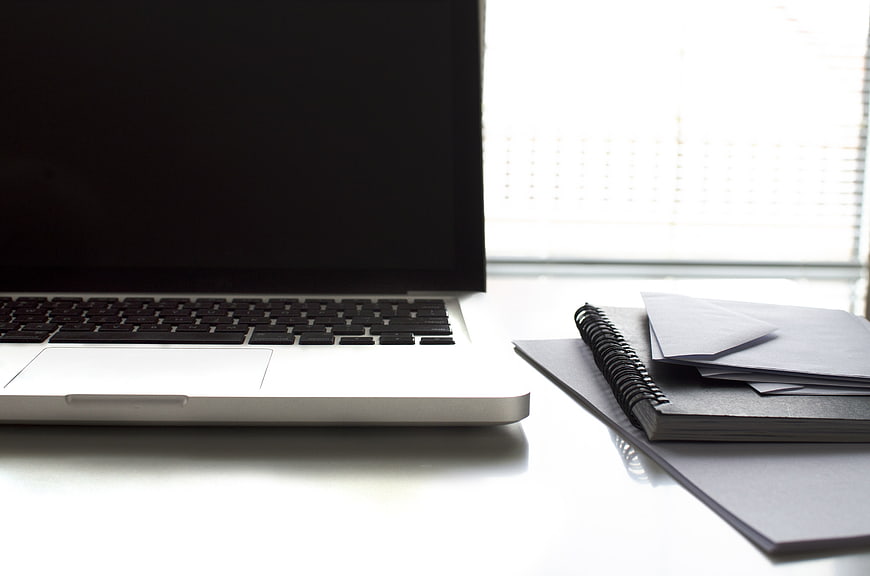 Minimalist workspace with laptop and notebook on white desk