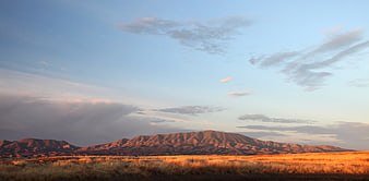 Golden Hour Desert Landscape with Rocky Mountains and Blue Sky