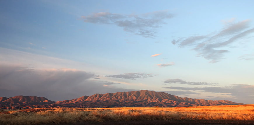 Golden Hour Desert Landscape with Rocky Mountains and Blue Sky