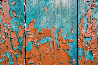 Textured turquoise and orange peeling paint on old wooden planks