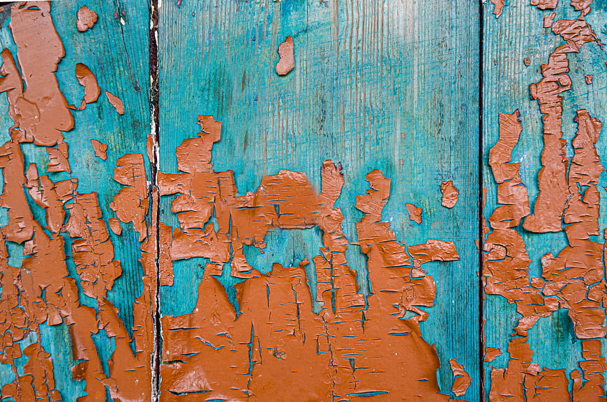 Textured turquoise and orange peeling paint on old wooden planks