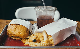 Classic fast food burger, crinkle-cut fries, and soda on a tray