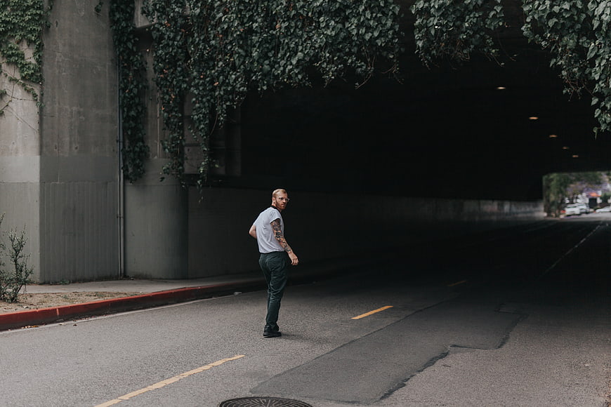 Man with tattoos standing in dark tunnel entrance