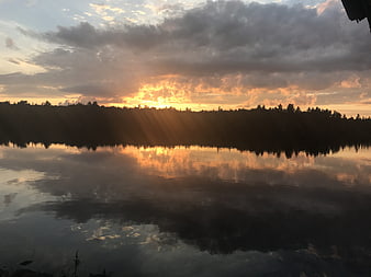 Dramatic sunset over lake with sun rays and reflection