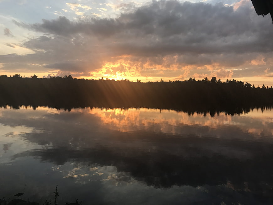 Dramatic sunset over lake with sun rays and reflection