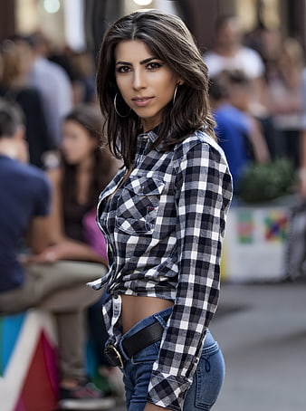 Young woman in plaid shirt and jeans posing in a busy city street