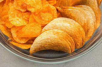 Close-up of potato chips and tortilla chips in a glass bowl