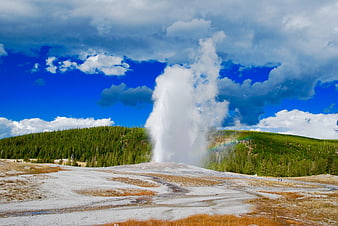 Majestic geyser erupting with rainbow in geothermal landscape