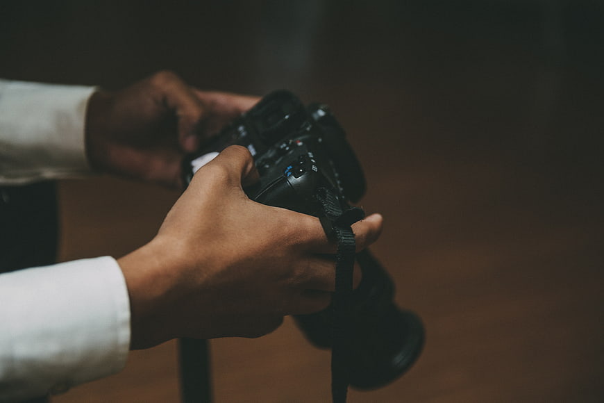 Close-up of hands holding a professional DSLR camera