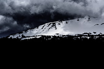 Dramatic Snow-Capped Mountain Peak Under Dark Stormy Clouds