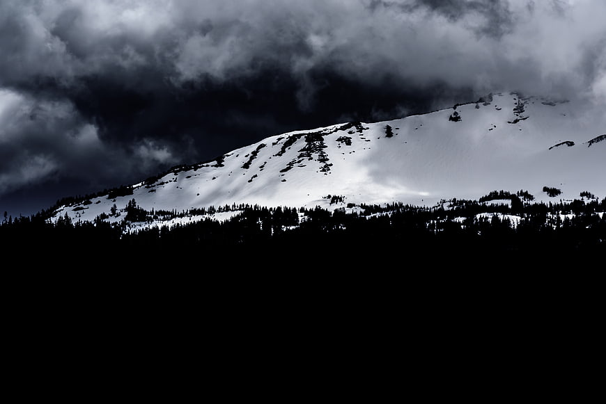 Dramatic Snow-Capped Mountain Peak Under Dark Stormy Clouds
