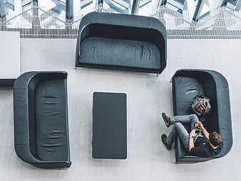 Top-down view of man relaxing on black sofa in modern lobby