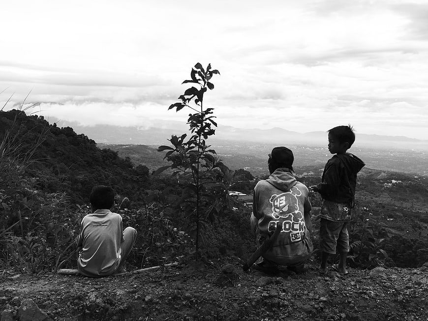Black and white photo of three children looking at mountain view