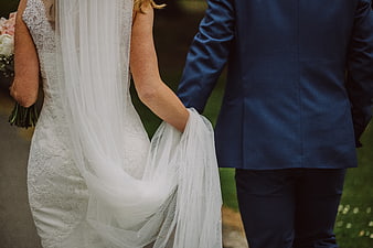 Bride and Groom Holding Hands in Blue Suit and White Dress