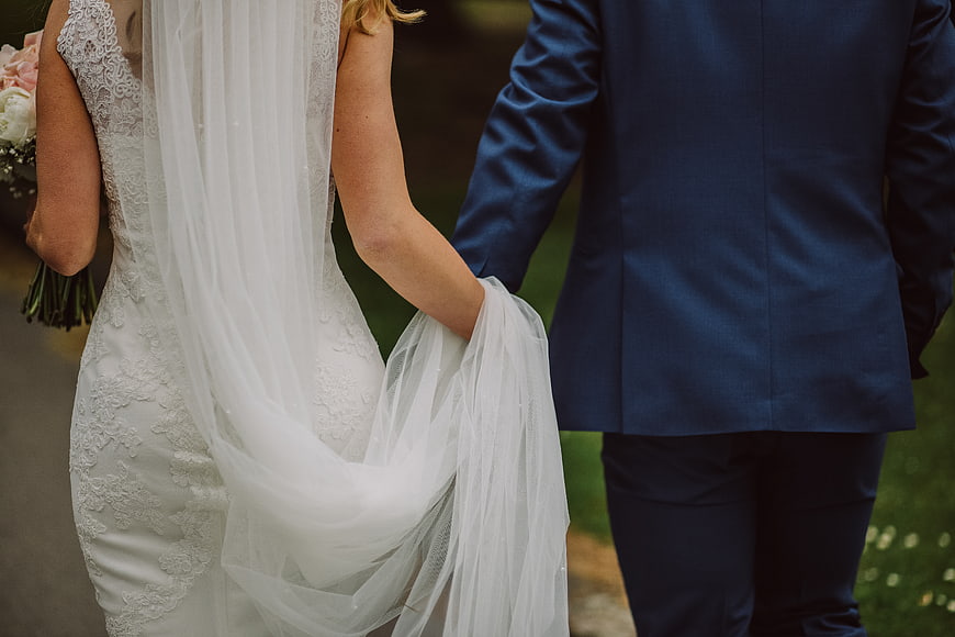 Bride and Groom Holding Hands in Blue Suit and White Dress