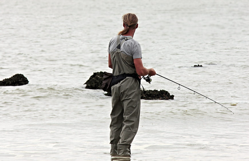 Man Fishing in Waders on Overcast Coast