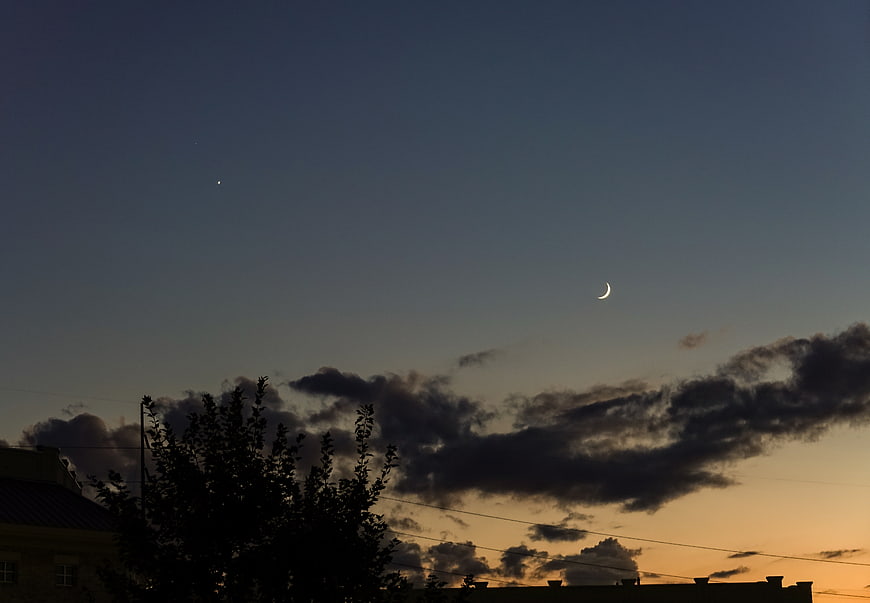 Crescent Moon and Star at Dusk Over Silhouetted Trees