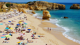Busy Summer Beach with Golden Cliffs and Turquoise Ocean